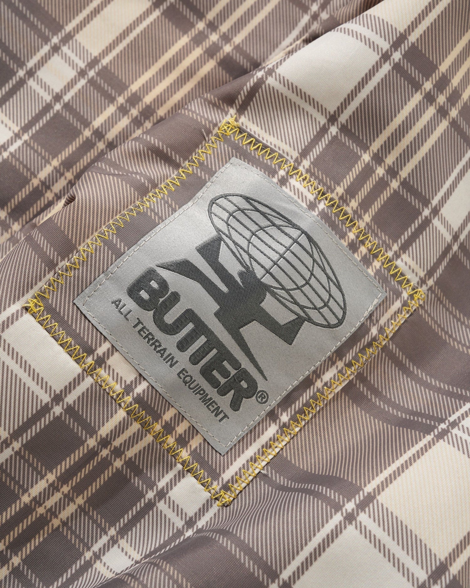 Butter All Terrain Equipment logo on plaid fabric