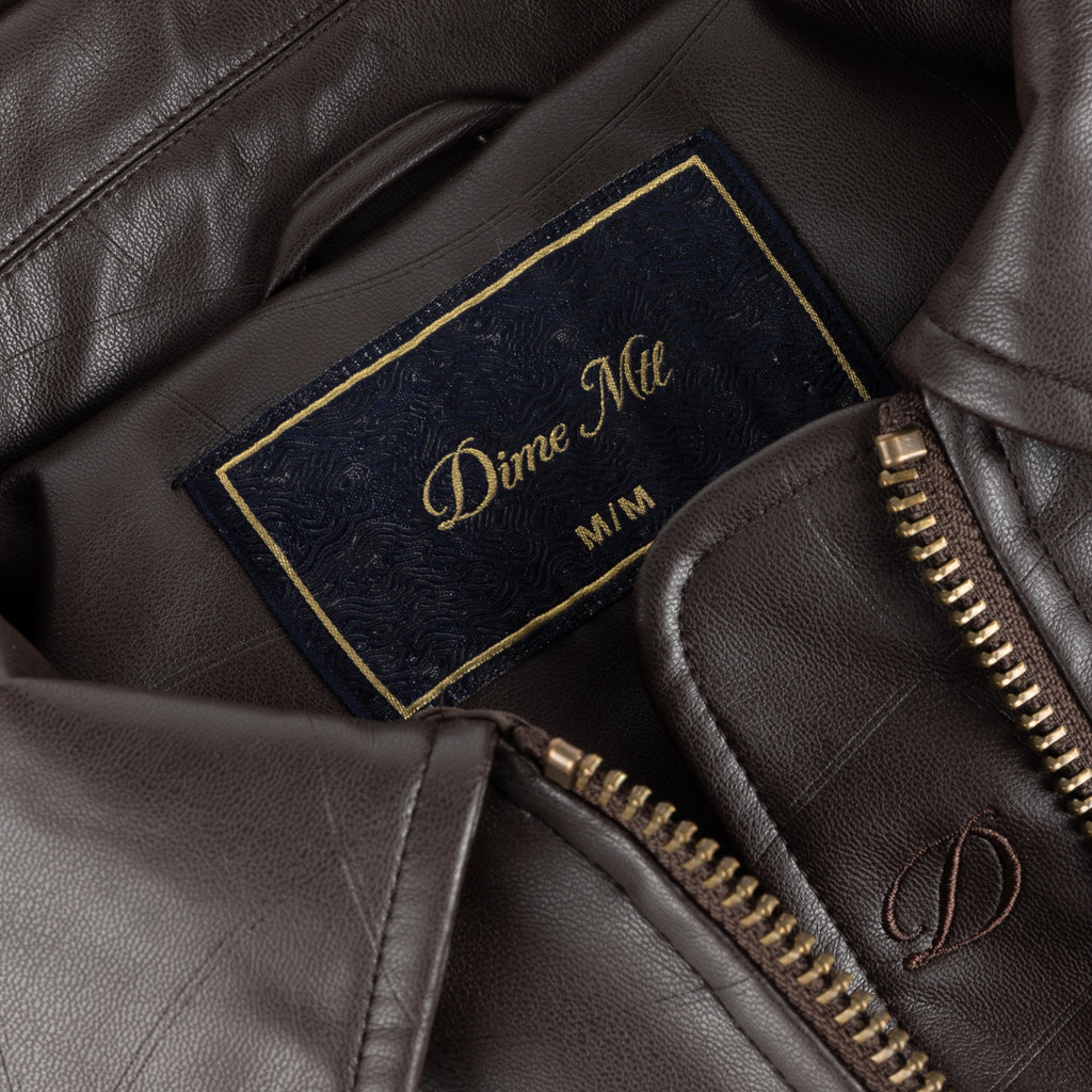 Close-up of a brown leather jacket with a brand label inside