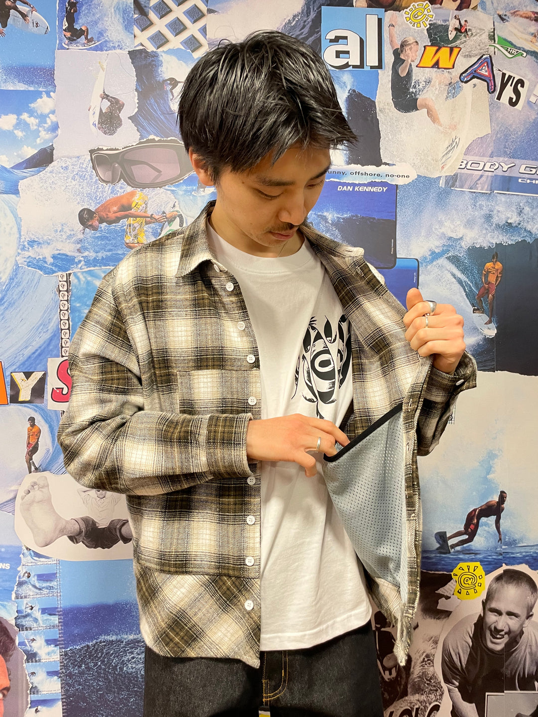 Person wearing a plaid shirt over a graphic t-shirt in front of a collage background