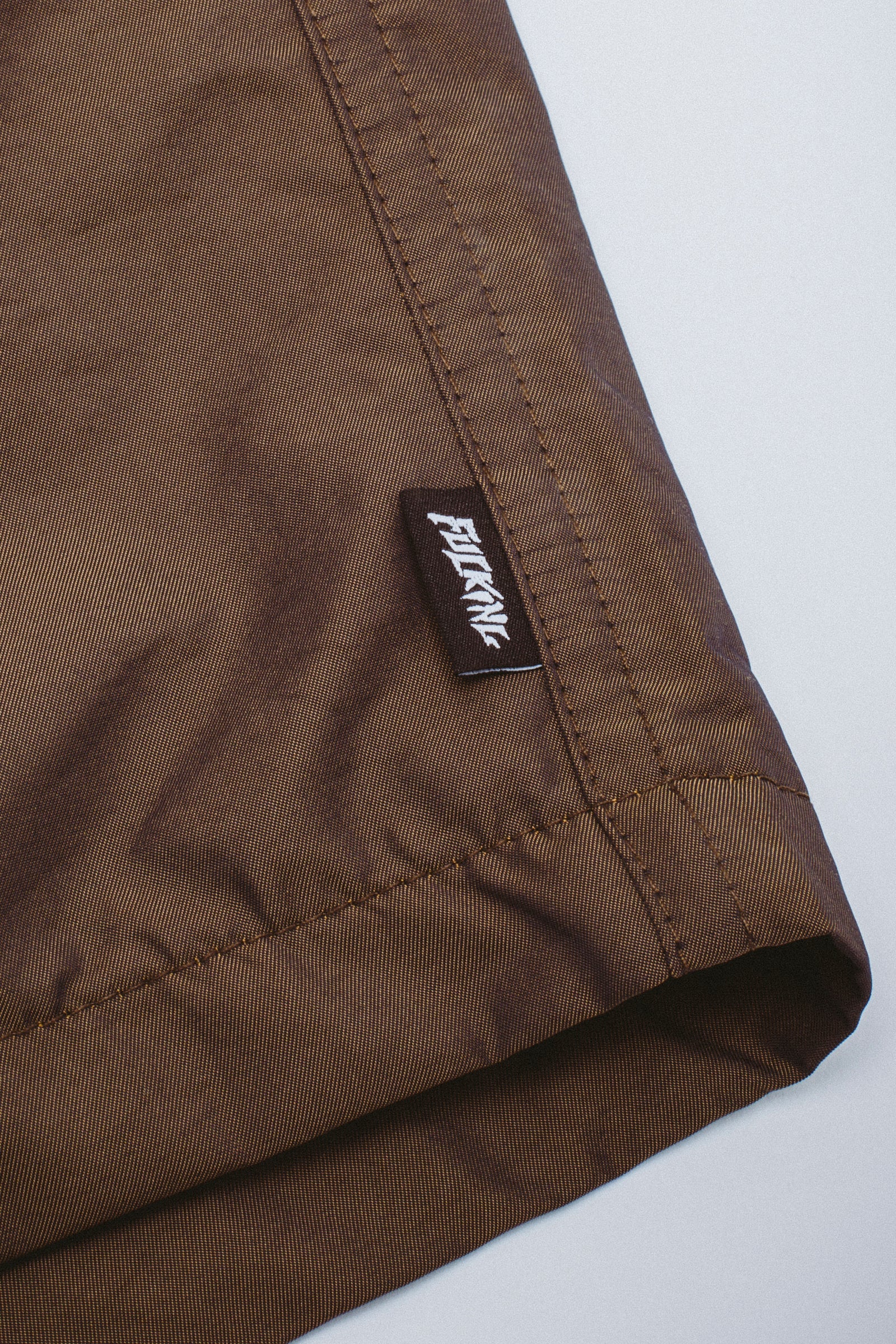 Close-up of brown fabric with a brand label on a white background