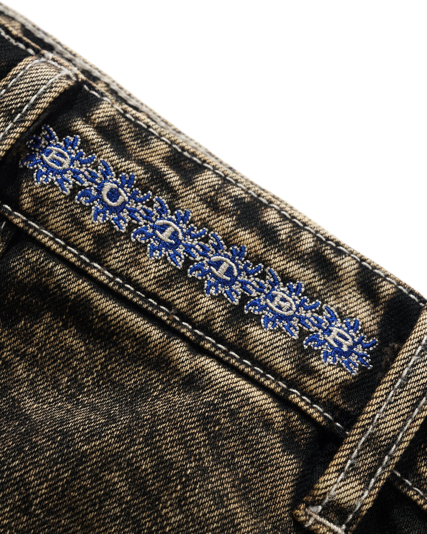Close-up of denim fabric with blue floral embroidery on a white background