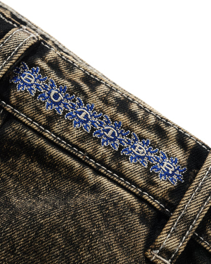 Close-up of denim fabric with blue floral embroidery on a white background