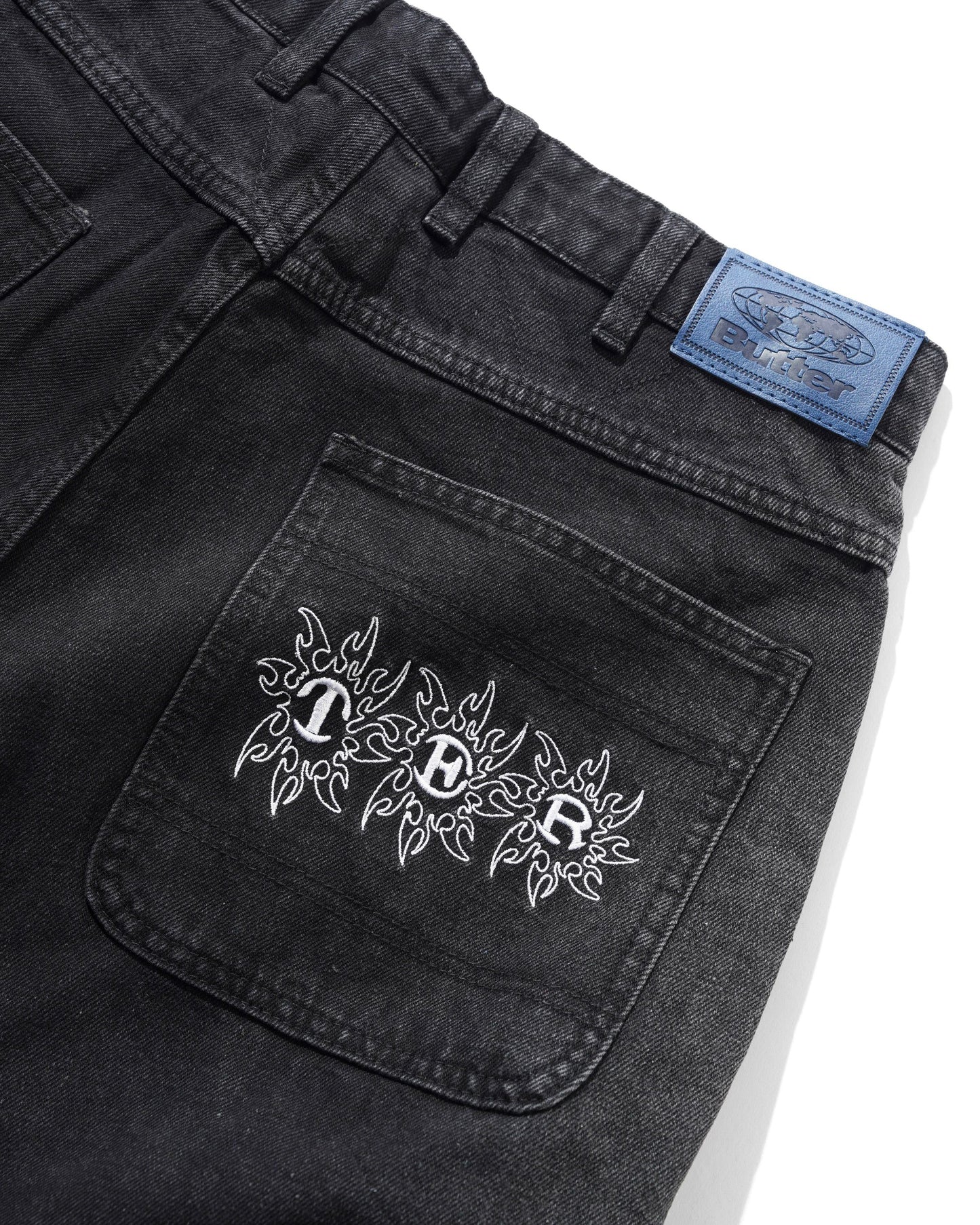 Black denim pocket with white embroidery and a blue label on a white background