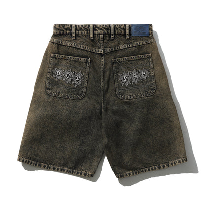 Brown denim shorts with embroidered designs on a white background