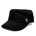 A black military-style cap with a curved brim and a small gold embroidered monogram logo on the side, shown against a plain white background.