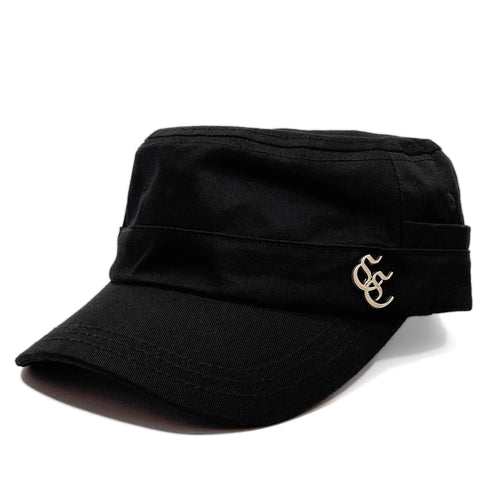 A black military-style cap with a curved brim and a small gold embroidered monogram logo on the side, shown against a plain white background.