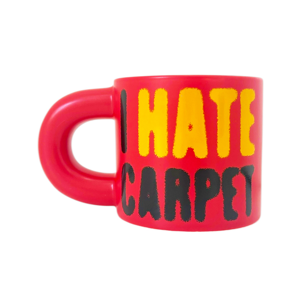 Red mug with yellow and black text 'I HATE CARPET' on a white background