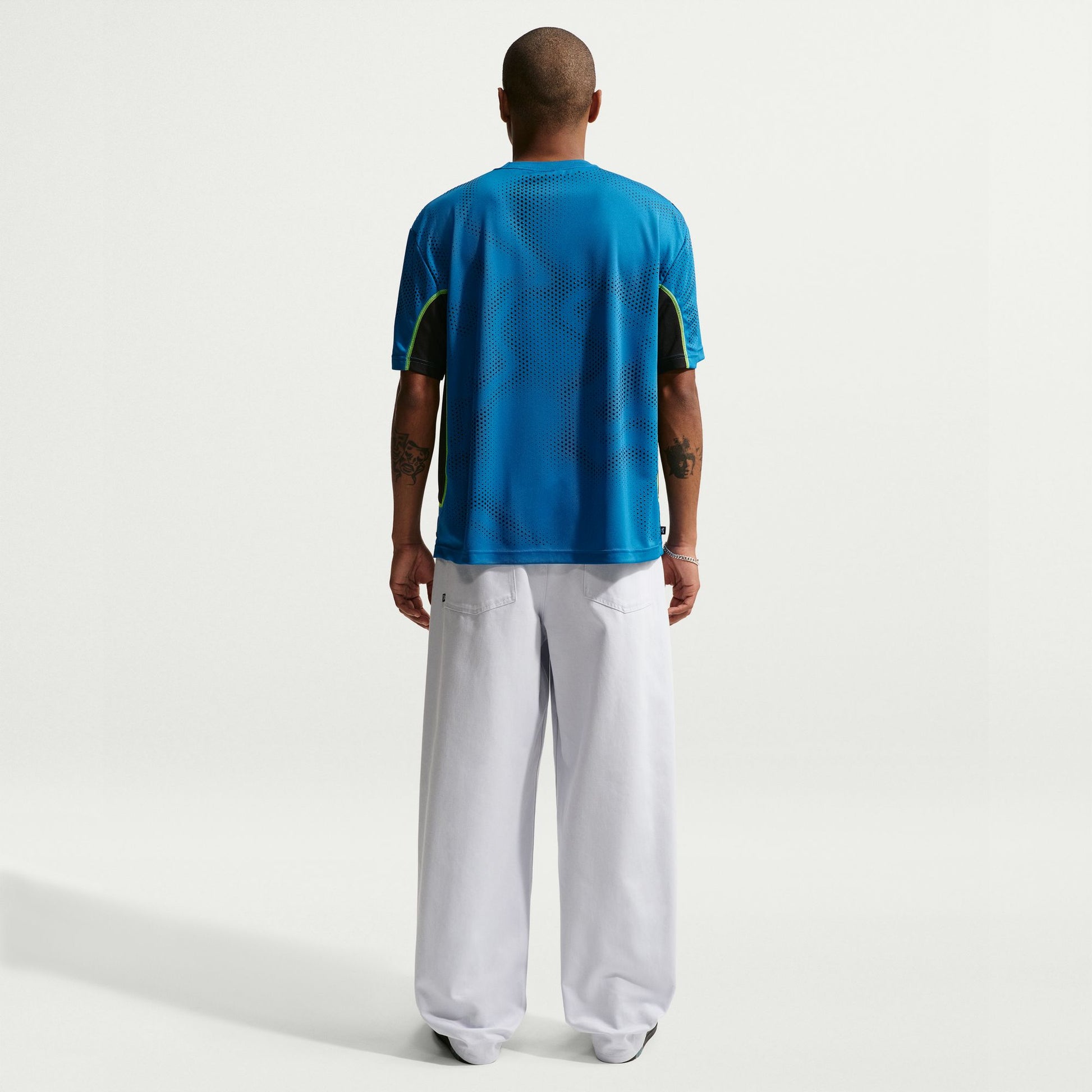 Person wearing a blue sports jersey and white pants on a white background