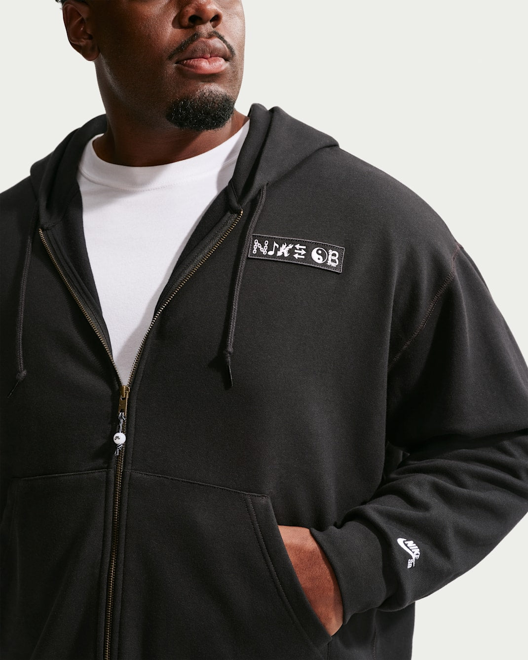 Person wearing a black hoodie with a logo on the chest against a white background