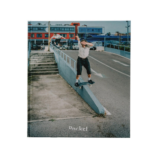 skateboarder performing tricks on a ledge with a cityscape background.