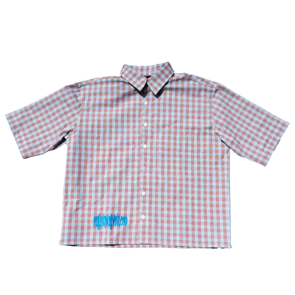 A short-sleeve button-up shirt with a pink and white gingham check pattern, featuring a small blue graphic on the lower left front, displayed flat against a white background.