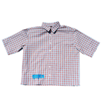 A short-sleeve button-up shirt with a pink and white gingham check pattern, featuring a small blue graphic on the lower left front, displayed flat against a white background.
