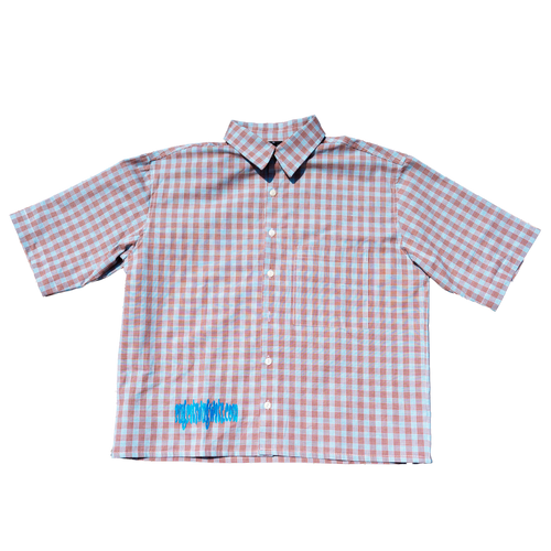 A short-sleeve button-up shirt with a pink and white gingham check pattern, featuring a small blue graphic on the lower left front, displayed flat against a white background.